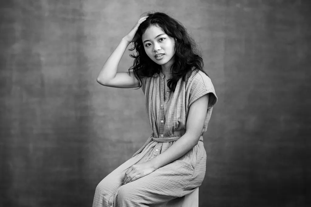 Black and white seated portrait of a young woman with her hand in her hair
