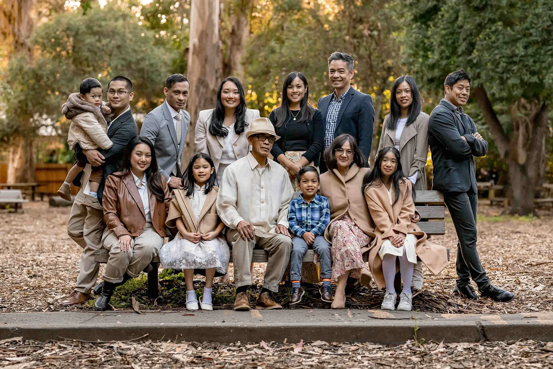 Extended family portrait gathered on a park bench outdoors
