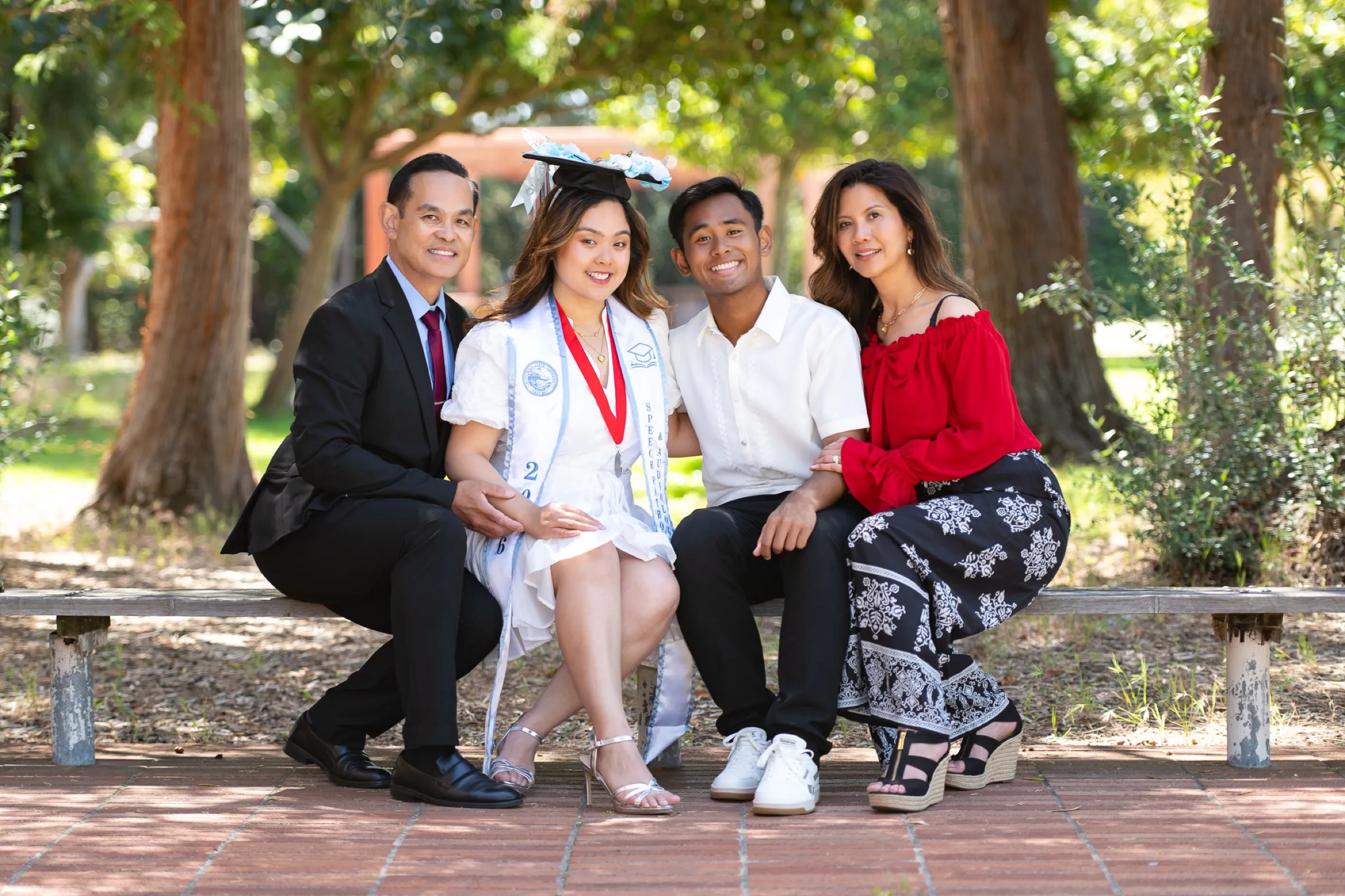 Family celebrating a college graduation together on a park bench