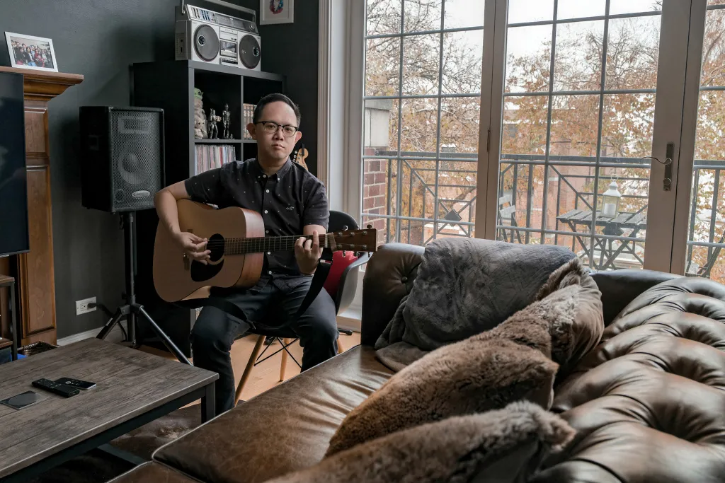 Man playing acoustic guitar in a living room at home