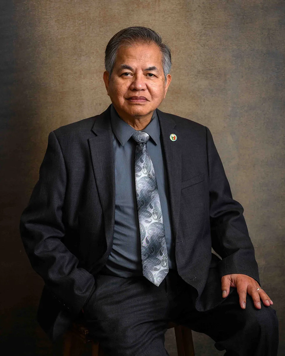 Older man in a suit and tie seated for a studio portrait