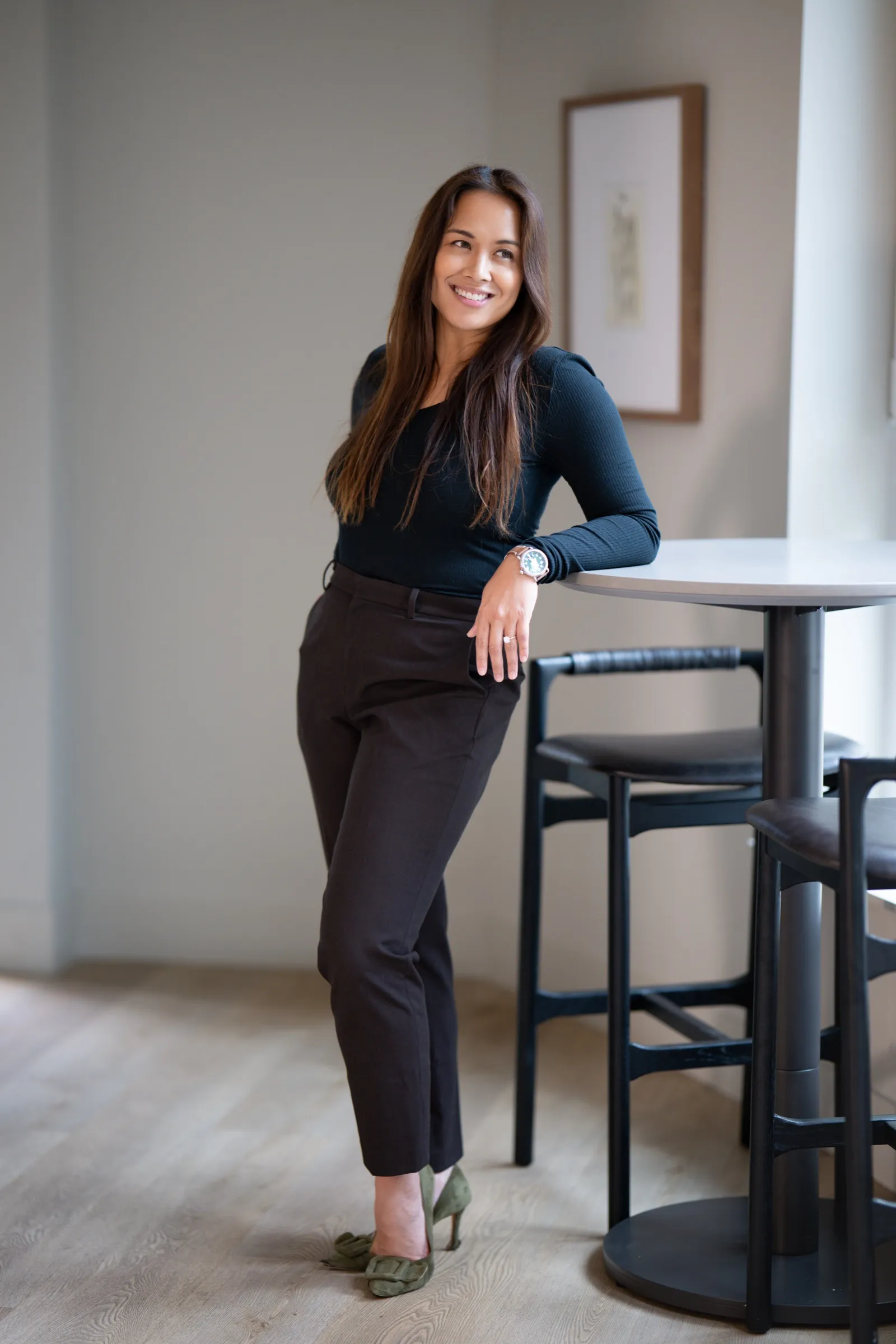 Woman in business attire leaning against a table for a personal branding portrait