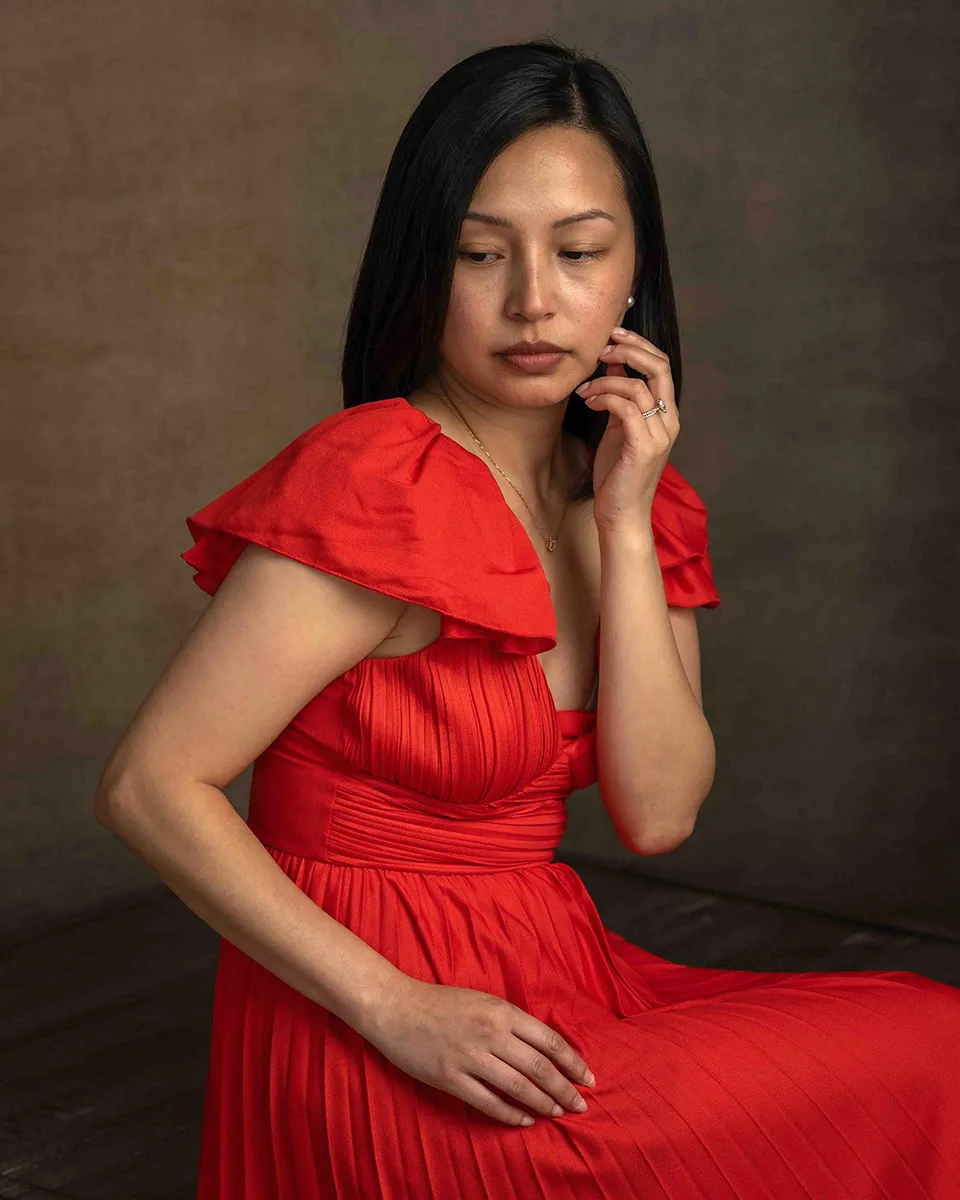 Woman in a red dress touching her earring for a studio portrait