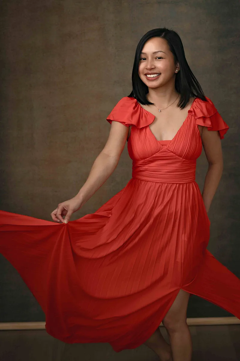Woman twirling in a red dress, smiling for a studio portrait